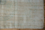 Distressed vintage Oushak rug's worn ivory pile, subtle green, and secured side selvage.