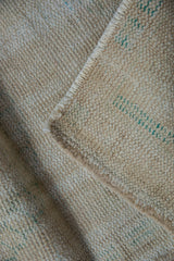Reverse side of a vintage distressed Oushak rug, showing foundation, selvage, and green marks.