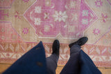 Distressed pile on a vintage Oushak rug with bubblegum pink medallion and terracotta border.