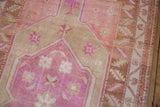 Distressed Oushak rug detail showing pink medallion, germinating blossoms, and beige field.