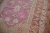 Distressed Oushak rug, bubblegum pink field with beige germinating blossoms and serrated border.
