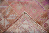 Folded corner detail showing distressed pink and beige Oushak pile and hand-knotted foundation.