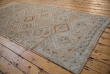 Distressed Oushak runner with geometric medallions and hook-and-latch motif in ivory, blue, brown.