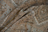 Distressed Oushak rug texture revealing muted geometric motifs in brown, ivory, and blue.