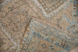 Distressed Oushak rug pile in ivory and powder blue, revealing its hand-knotted foundation and selvage.
