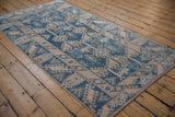Distressed indigo blue and beige geometric field with vine border motifs on a vintage Melas rug.