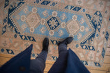 Distressed vintage Melas rug with soft powder blue field and navy, peach, ivory motifs.