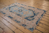 Distressed Melas rug corner with intact selvage, navy geometric border, and blush field.