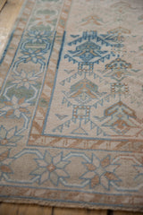 Low, even pile on a distressed Oushak rug showing its seafoam and blue starburst border.