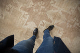 Textured distressed Oushak carpet, faded short pile revealing stepped beige and ivory patterns.