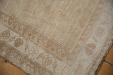 Distressed Oushak rug corner with short pile, abrashed field, and beige border.