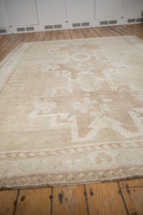 Oushak rug's geometric floral bouquets and wave border in soft beige and ivory hues.