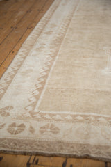 Distressed Oushak rug's beige and ivory wave design border and short pile detail.