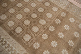 Distressed Oushak rug, short pile showing ivory paneled florals, wave motif border.