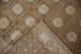 Distressed Oushak rug corner showing paneled floral pile and reciprocating wave border foundation.