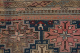 Close-up of antique Shirvan rug's intricate geometric borders, pawn design, and pink starburst motifs with fine wear.