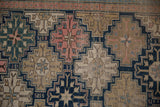 Close-up of antique Shirvan rug's fine weave, intricate stepped panels in navy, pink, and beige.