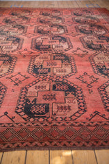 Vintage Ersari carpet displaying repeating dusty blush gul panels and charcoal navy border.