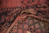 Vintage Ersari carpet folds revealing soft wool texture and blush, navy geometric design.