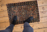 Distressed vintage Farahan Sarouk rug's dusty rose floral field and intricate navy boteh border.