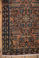 Vintage Farahan Sarouk rug corner showing dusty rose field and navy serpent border.