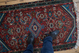 Vintage Hamadan rug's diamond medallion and Herati pattern in cherry red, teal, and blue.