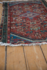 Worn vintage Persian Hamadan rug with cherry red Herati field, blue serpent border, and ivory fringe.