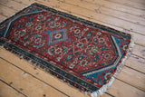 Vintage Hamadan rug upper corner, with dusty teal border, cherry red Herati field, and tattered fringe.