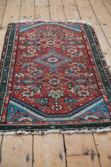 Side view of vintage Hamadan rug with dusty mallard teal green serpent border and cherry red field.