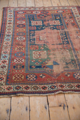 Antique Caucasian rug: exposed foundation, madder red, indigo, and worn pawn motif border.