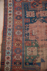Antique Caucasian rug detail showing indigo blue geometric border, madder red motifs, and foundation exposure.