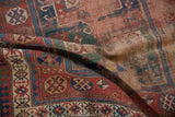 Worn antique Caucasian rug: madder red, indigo, green geometric pattern with foundation showing.