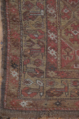 Worn hand-knotted pile on Antique Kurdish rug revealing geometric floral panels, visible foundation.