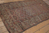 Antique Kurdish rug's wide floral border and geometric panels in dusty red, showing wear.