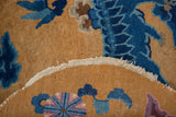Close-up of antique Peking rug's cobalt floral cloudband, short pile, and woven edge.