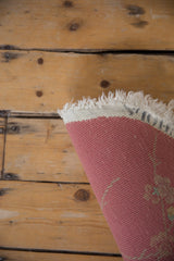Back of a Nichols Art Deco rug, showing original stamping on dusty pink plainweave and fringe.