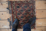 Tattered kilim ends and navy, terra cotta, ivory starbursts on antique Afshar rug.