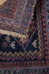 Fringe and detailed reciprocating pawn motif on a navy blue and terracotta Afshar rug.