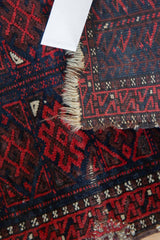 Storied fringe and woven section of an antique Belouch rug with madder root red motifs.
