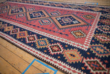 Close-up of serrated diamond motifs in blush and navy blue on a vintage Persian Kilim.