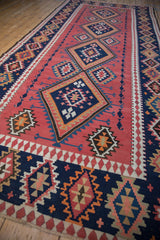 Serrated navy blue geometric diamond medallions on a cochineal blush vintage Persian Kilim.
