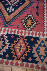 Close-up of vintage Persian Kilim rug's serrated geometric diamond and cross patterns in navy, blush.