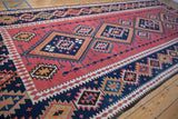 Vintage Persian Kilim runner: navy blue serrated diamond medallions on a cochineal blush field.