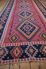 Navy blue geometric border and dusty cochineal field with serrated diamond motif on the vintage Kilim runner.