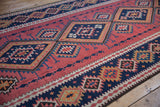 Close-up of Vintage Persian Kilim runner with dusty blush field, navy diamond motifs, and zig-zag borders.