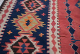 Hand-woven Persian Kilim rug detail with navy geometric diamonds and blush samovar motifs.