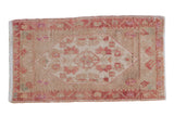 Distressed Oushak mat, faded raspberry pinwheel medallion on a beige field.