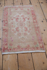 Bottom edge of vintage Oushak rug mat showing secured ivory fringe and worn pile.