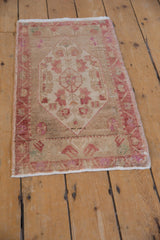 Upper left corner of vintage distressed Oushak rug, showing faded raspberry blossoms and wear.