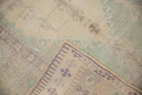 Distressed Oushak rug corner, showing short pile texture and hand-knotted geometric border reverse.